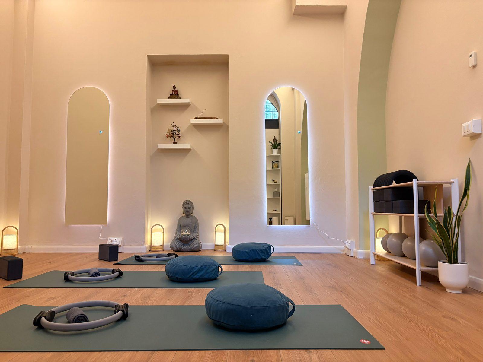 The Kala practice room: mats, cushions and Pilates rings laid out before two backlit arched mirrors and a small shrine