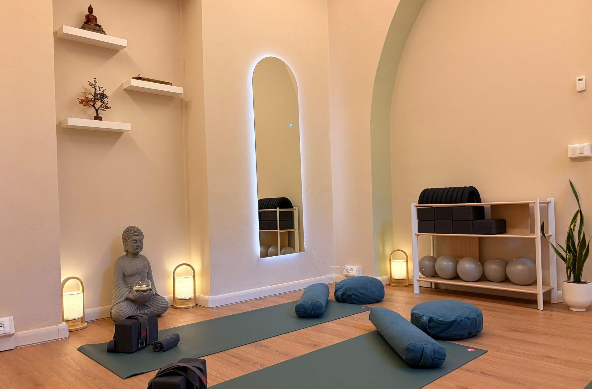The Kala practice room: mats, bolsters and meditation cushions beside the Buddha statue, lanterns and shelves of props
